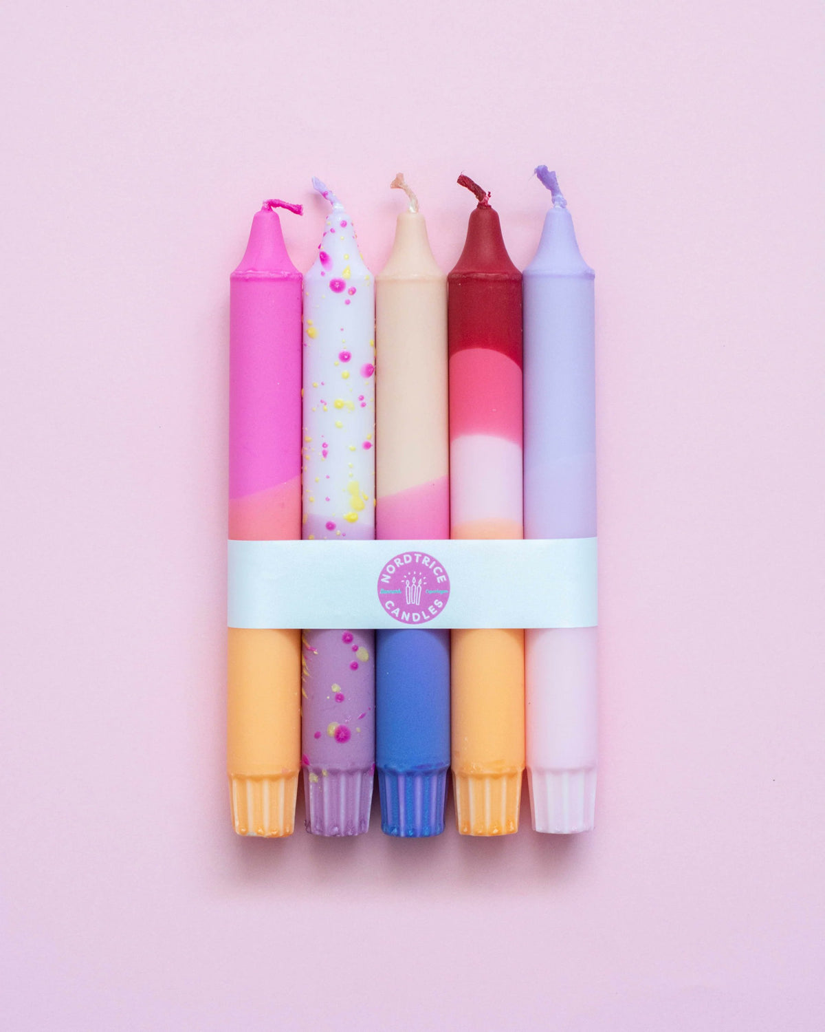 Nordtrice pastel sunset taper candles 5-pack bundled with white band on pink background