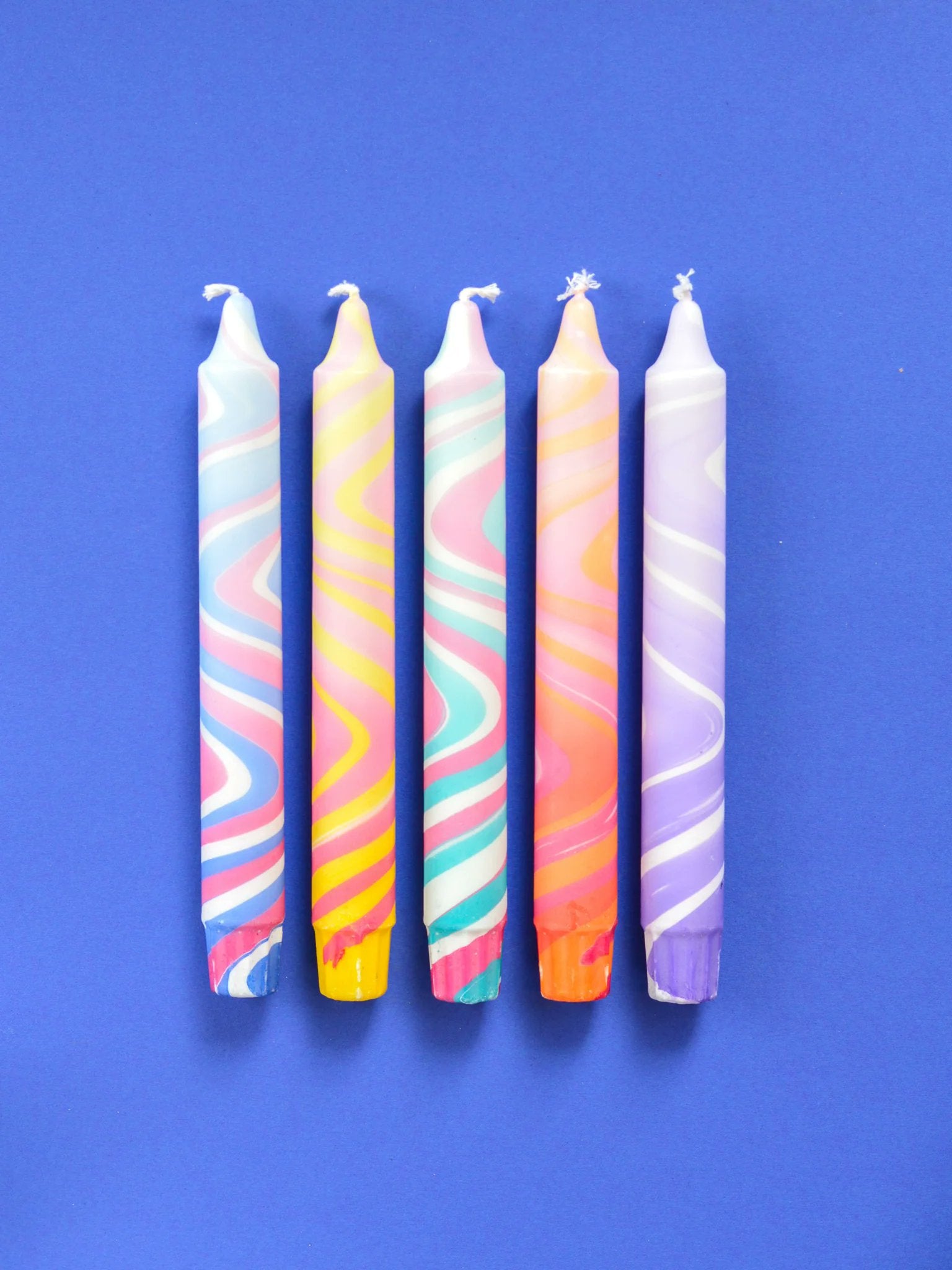 Nordtrice summer marble taper candles 5-pack loose on blue surface showing full swirl pattern