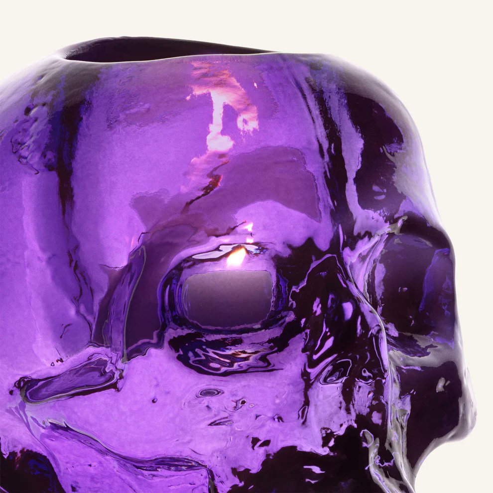 Close-up of Kosta Boda Still Life purple glass skull votive showing glass texture and candlelight reflection